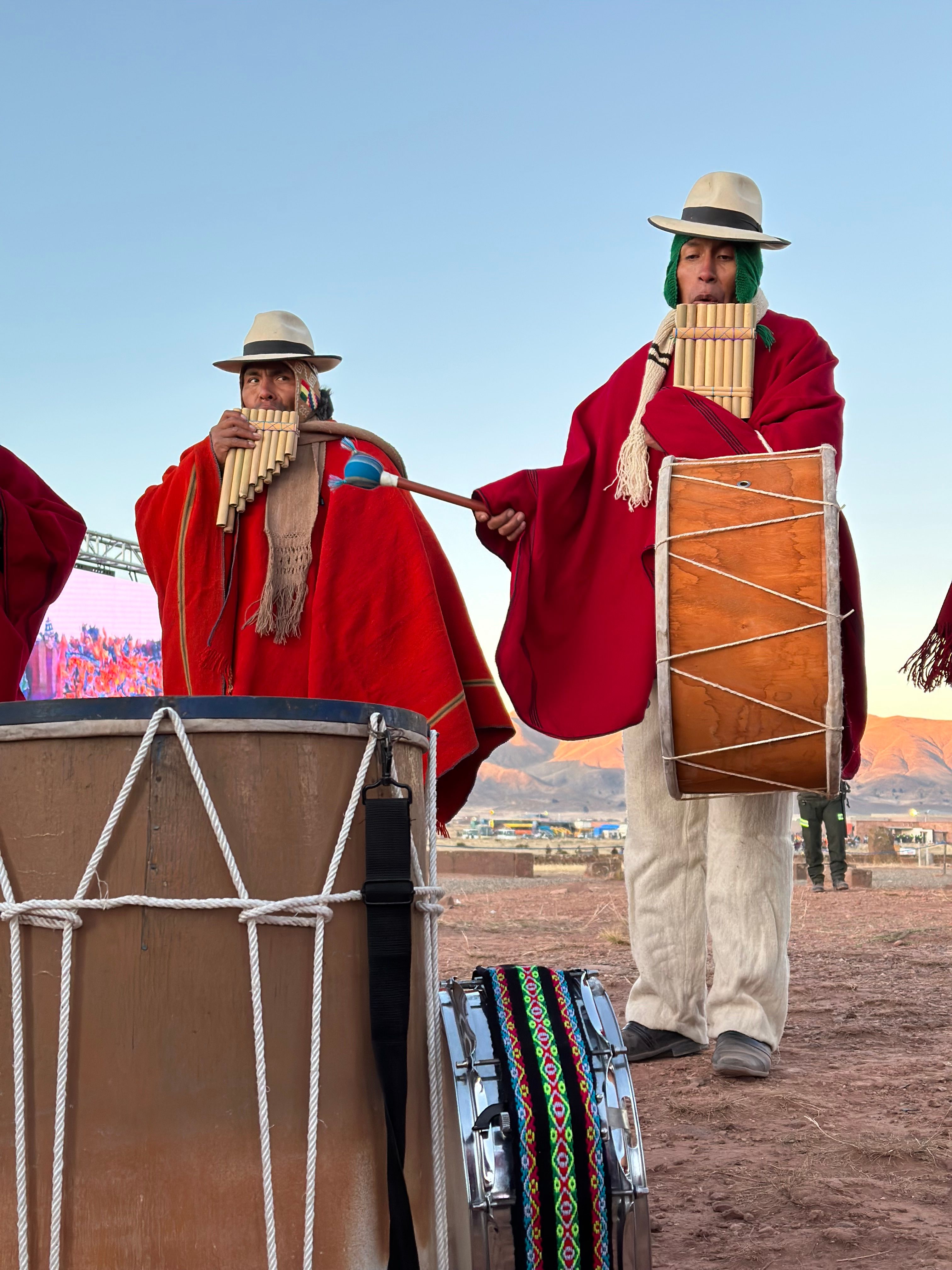 Músicos en Tiwanaku, Bolivia, tocando instrumentos tradicionales con atuendos vibrantes.