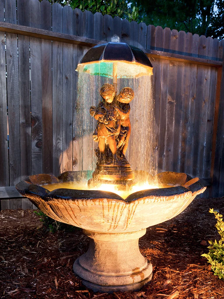 Outdoor living water feature and evening landscape lighting by Lavish Gardens Landscape