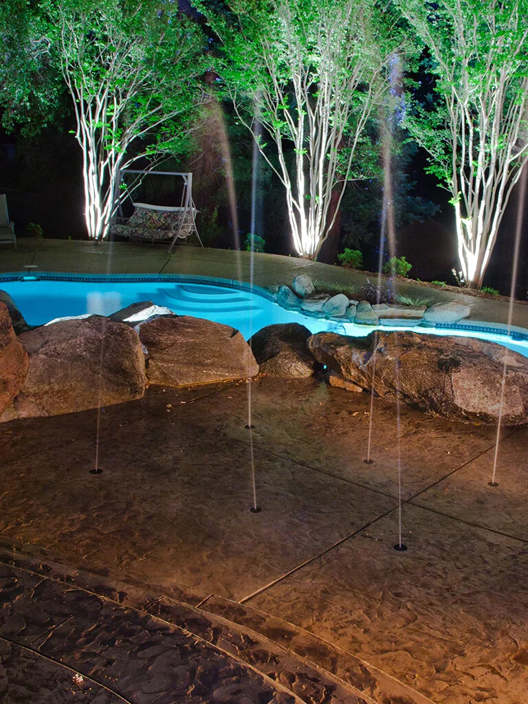 Auburn poolside trees, boulder accents, and low-voltage landscape lighting by Lavish Gardens Landscape