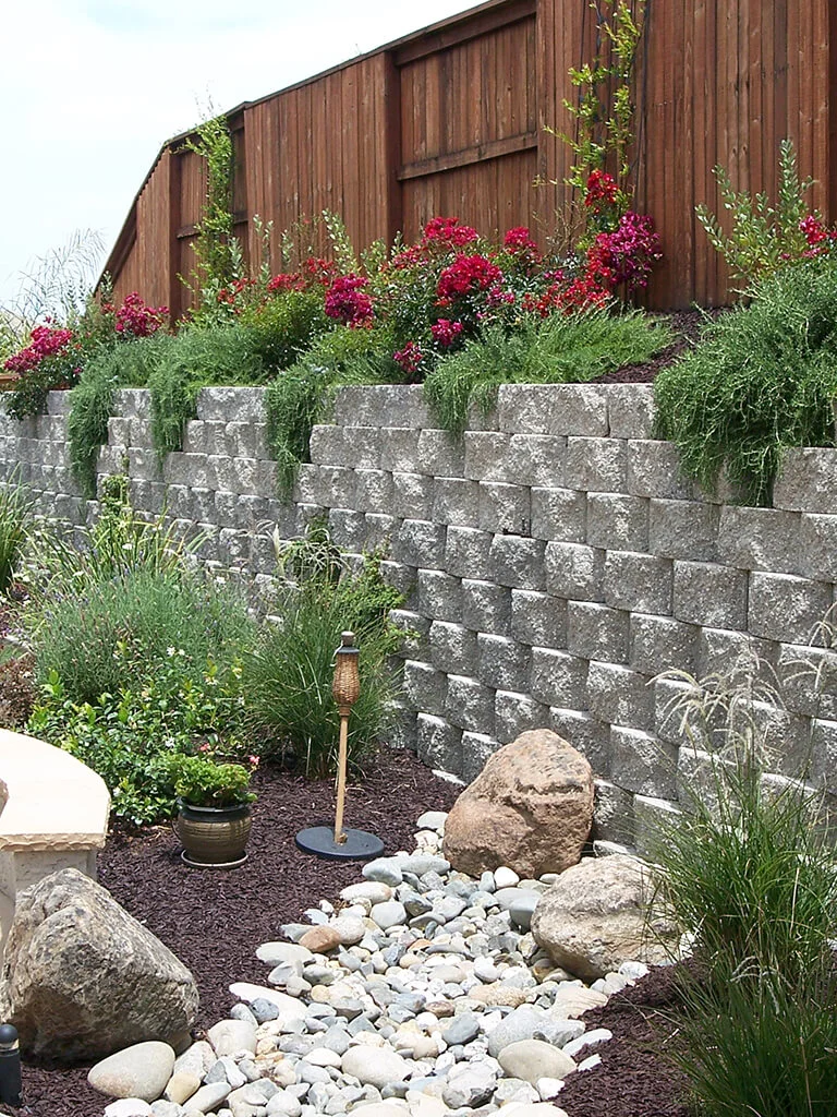 Roseville retaining wall, planting, river rock, and landscape lighting by Lavish Gardens Landscape