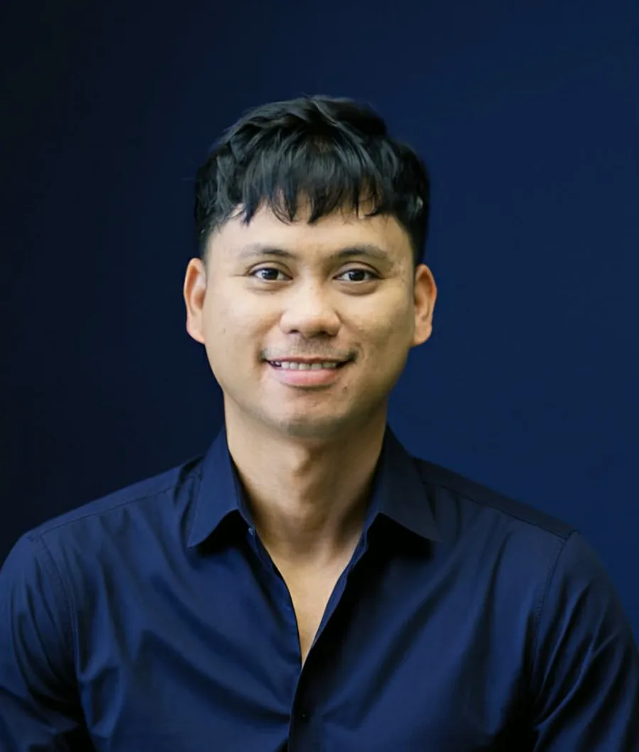 Portrait of Gio in a navy shirt, smiling