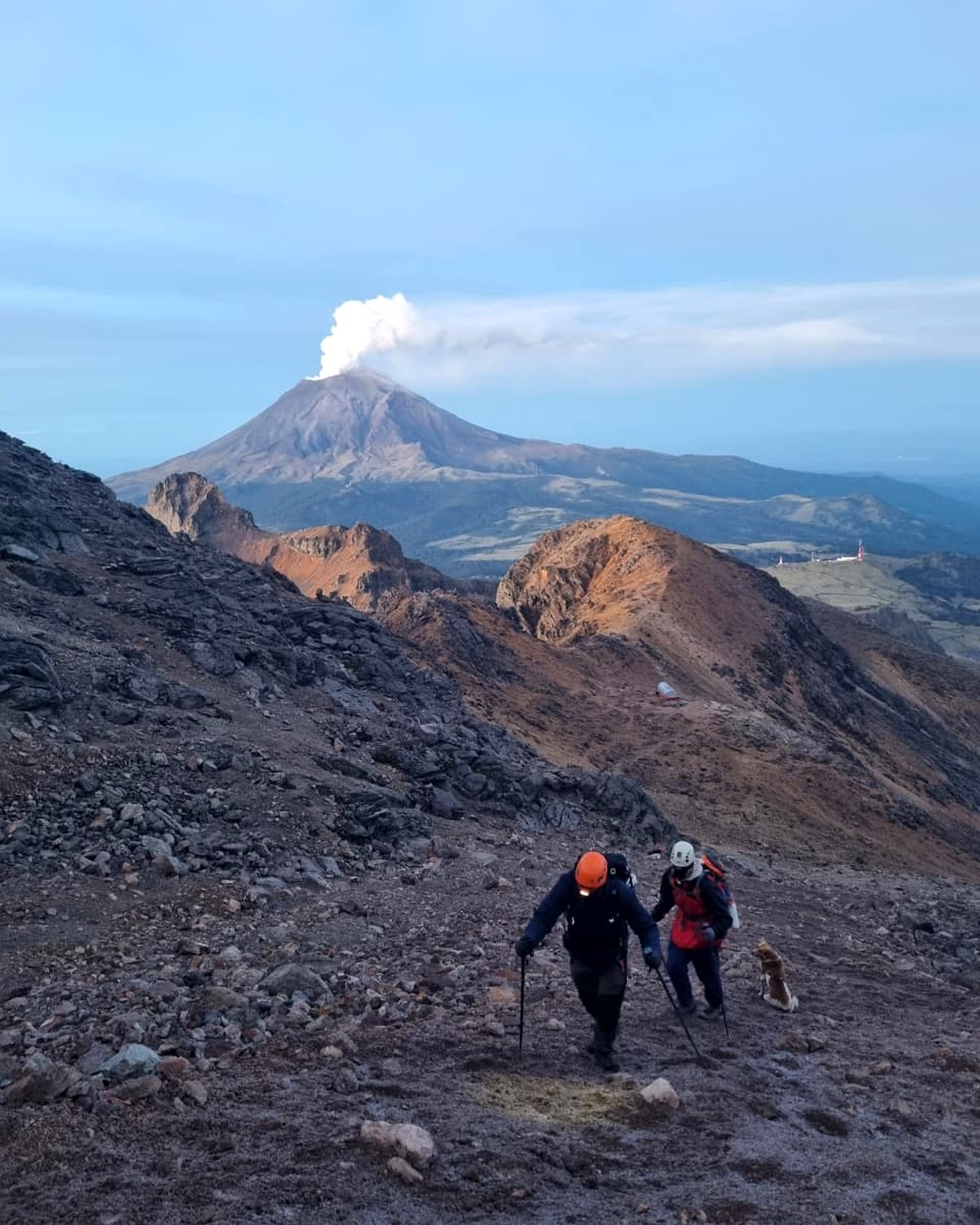 A line of climbers on Iztaccíhuatl with Popocatépetl smoking in the distance