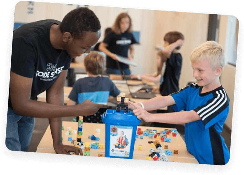 Instructor and young boy smiling while building with blocks