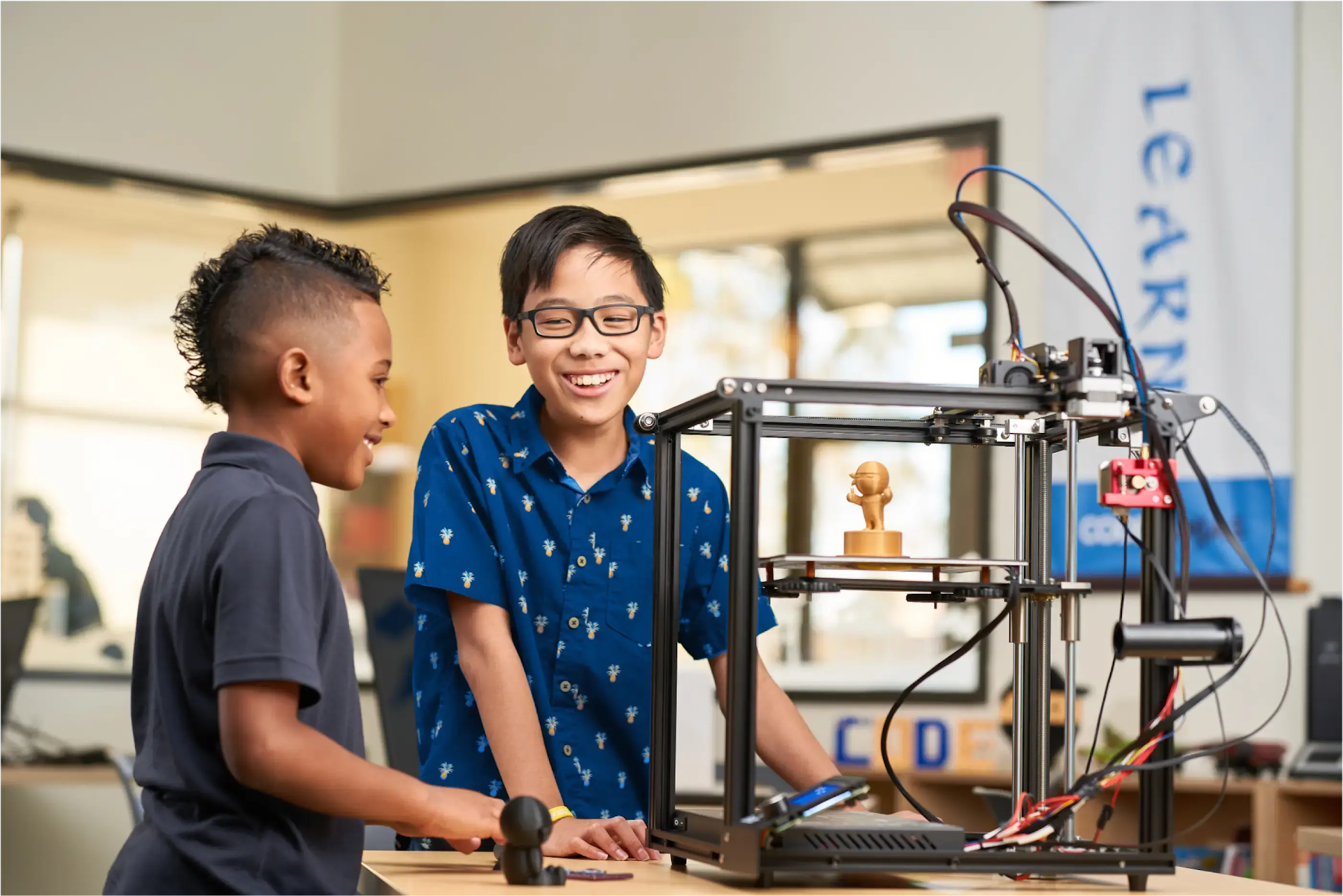 Two boys enthusiastically watching a 3D printer operate