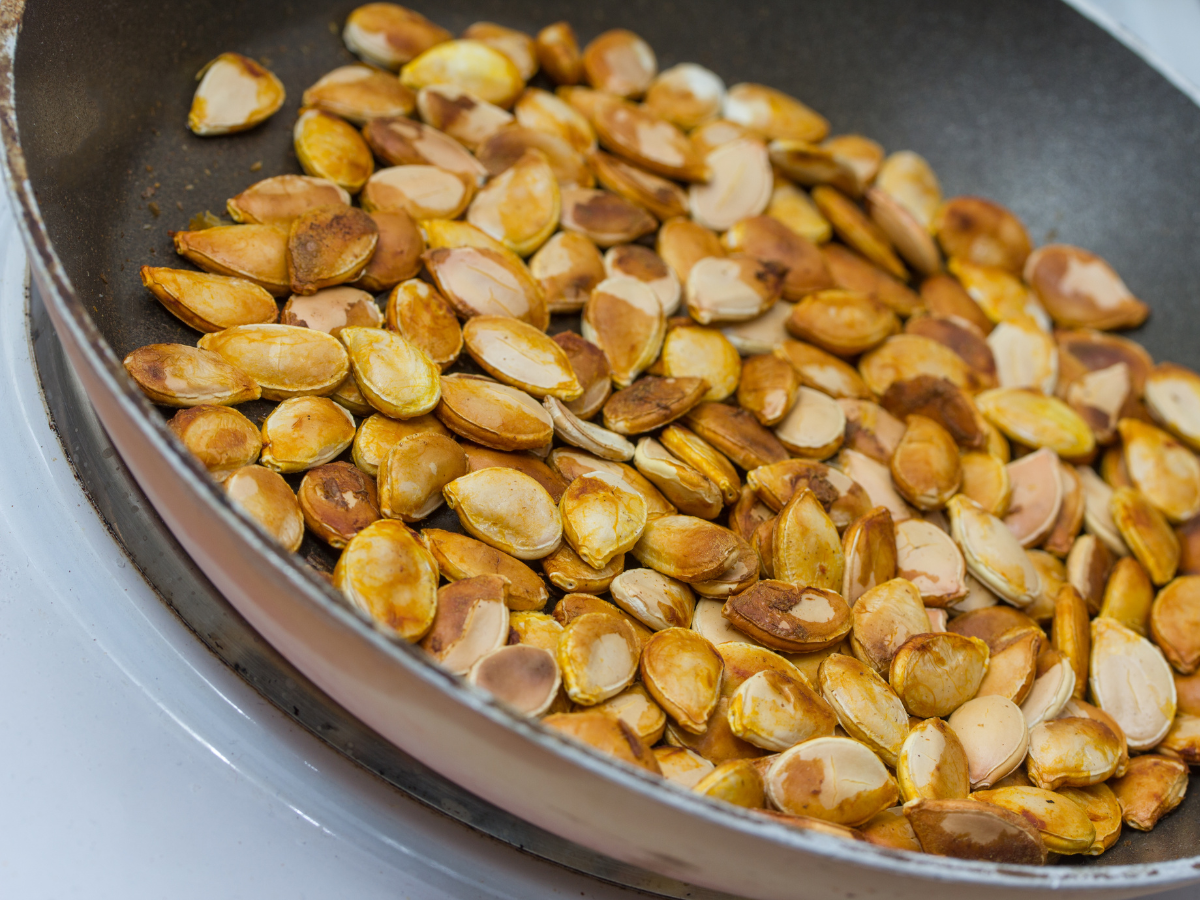 Close-up of golden-brown pumpkin seeds in a pan. Close-up of golden-brown pumpkin seeds in a pan.