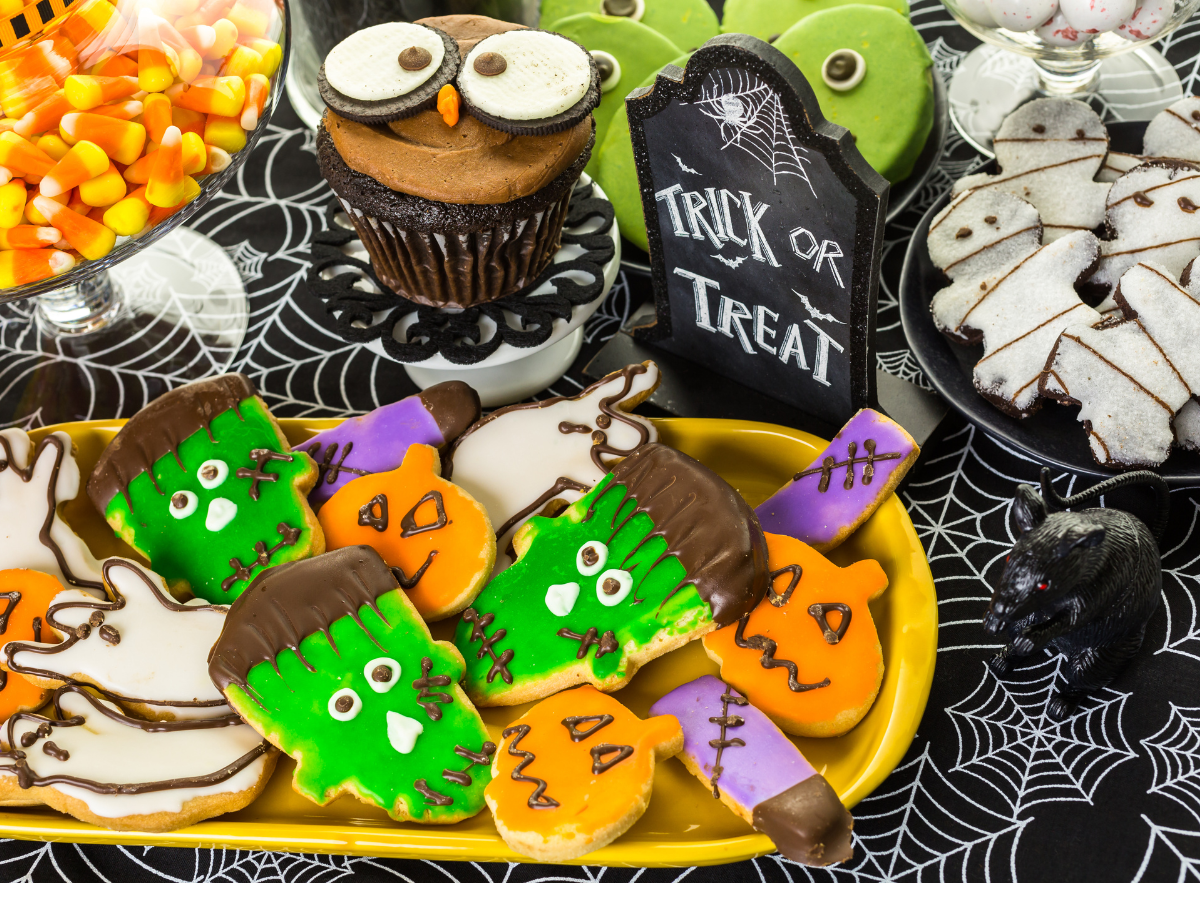 Halloween display with colorful monster, pumpkin, and ghost cookies, an owl cupcake, and candy corn. Halloween display with colorful monster, pumpkin, and ghost cookies, an owl cupcake, and candy corn.