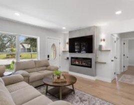 Renovated open living room with a fireplace wall and light wood floors