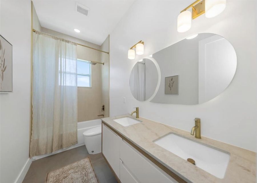 Finished Dreamway bathroom with slatted wood vanity, round mirror and tub shower