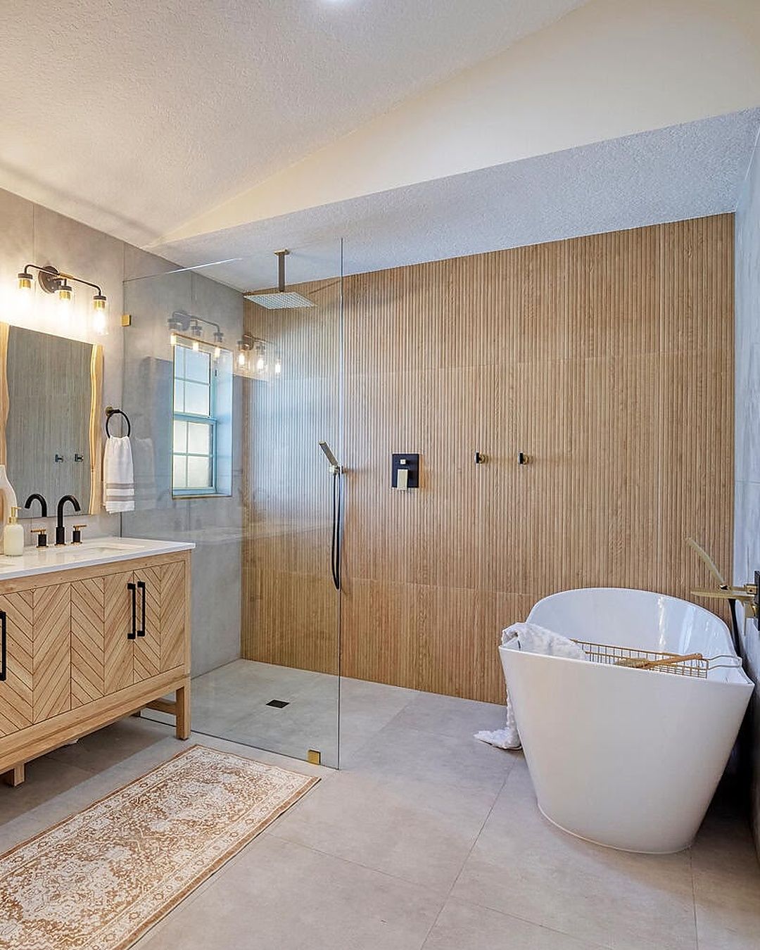 Finished Dreamway bathroom with a walk-in glass shower, wood-slat tile wall and freestanding tub