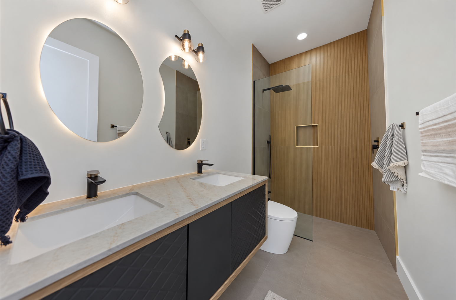 Finished bathroom with a double vanity, backlit mirrors and tub shower