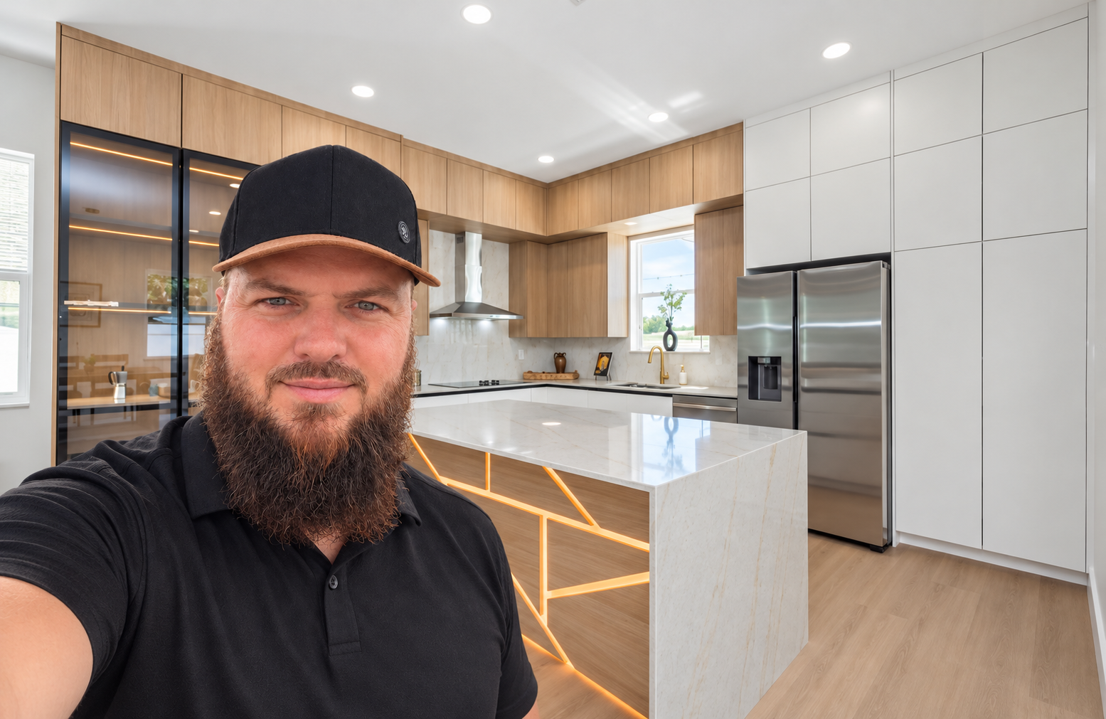 Alban, owner of Dreamway Construction, in a finished modern kitchen with wood cabinetry and a lit waterfall island