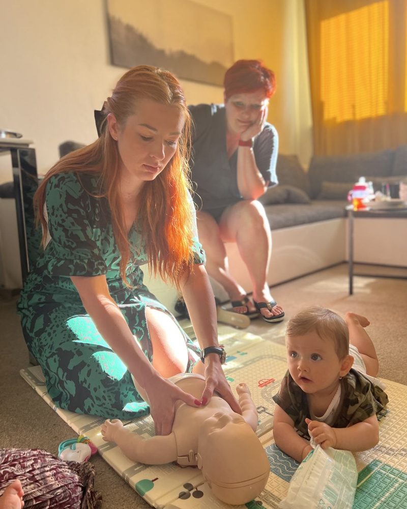 Maminka zkouší první pomoc na figuríně miminka u nich doma