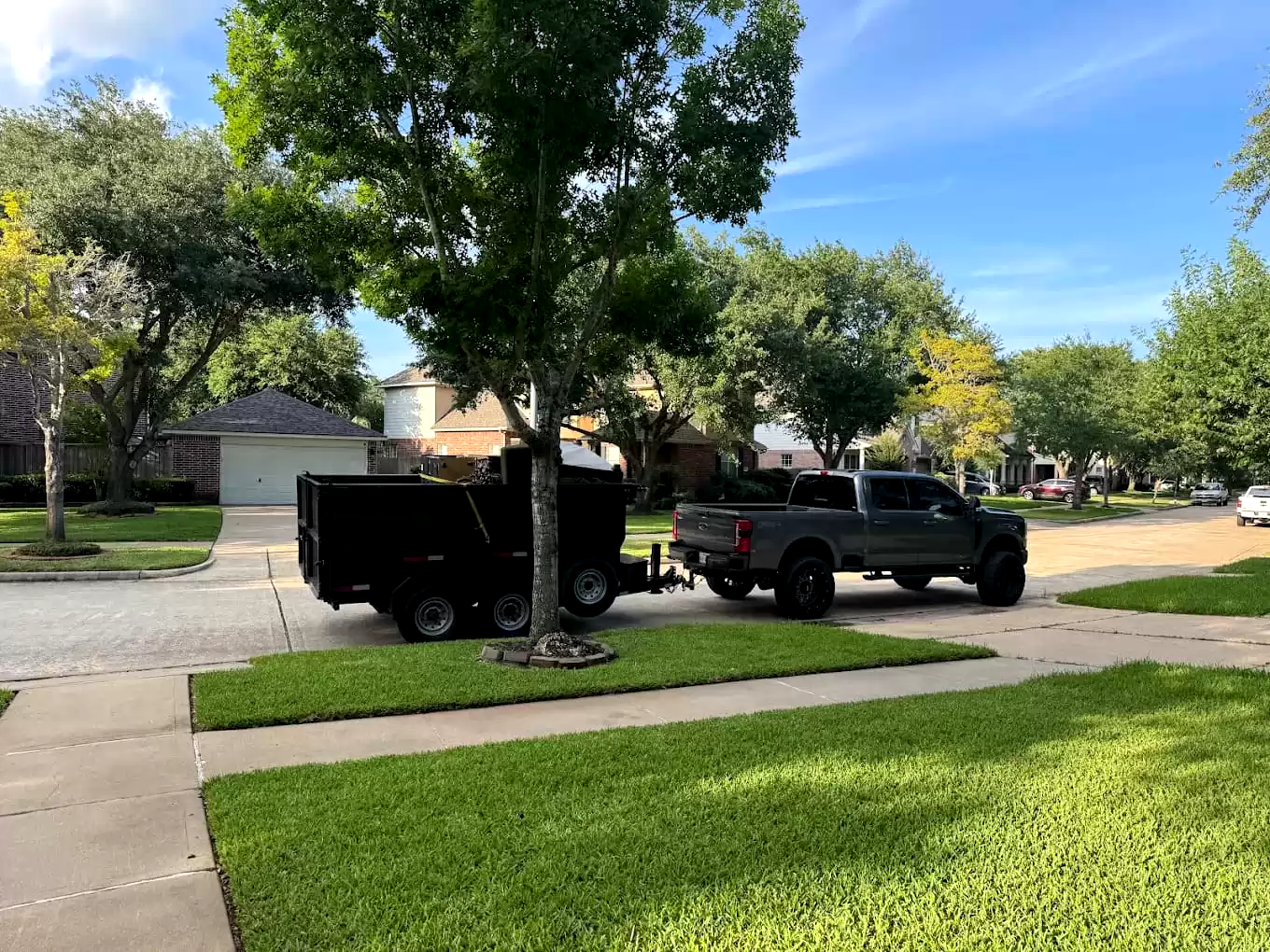 Pickup truck and dump trailer parked along a residential curb