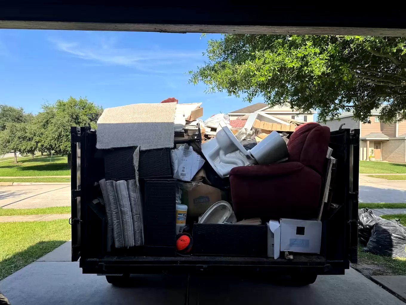 Armchair, mattress and household items loaded in a dump trailer