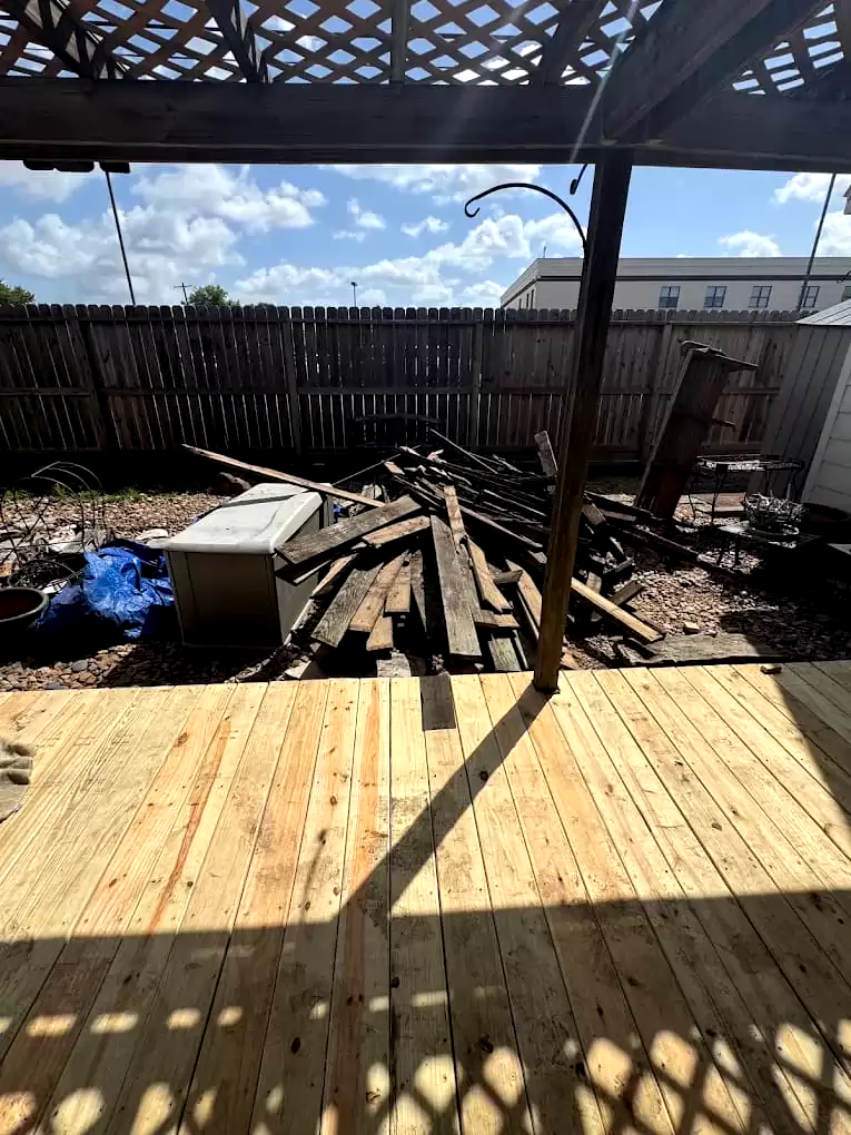 Wood boards and debris beneath a backyard pergola