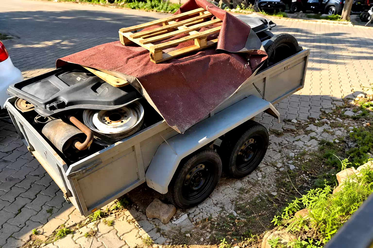 Utility trailer loaded with carpet, tires and a pallet