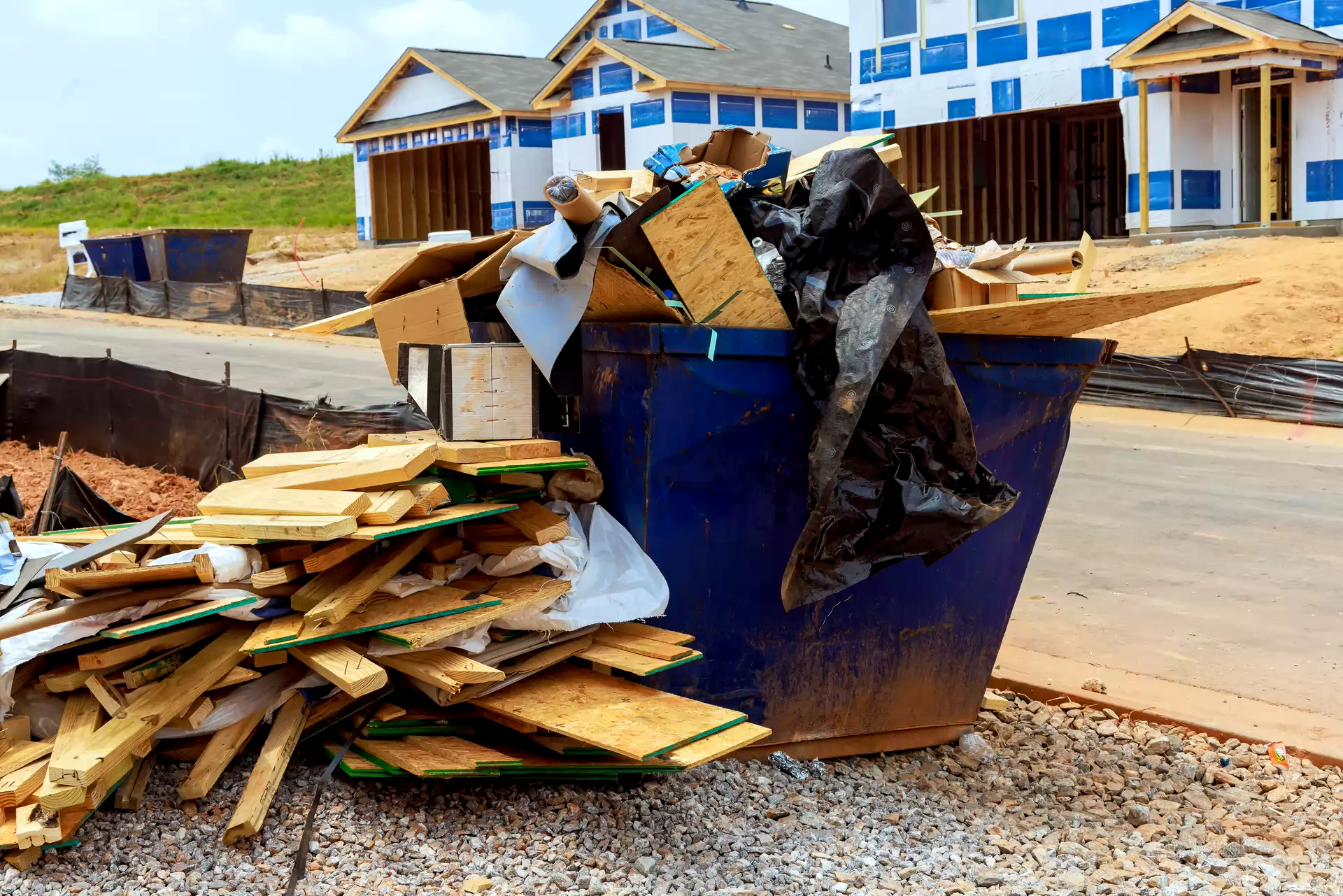 Lumber and construction debris beside a dumpster at a building site