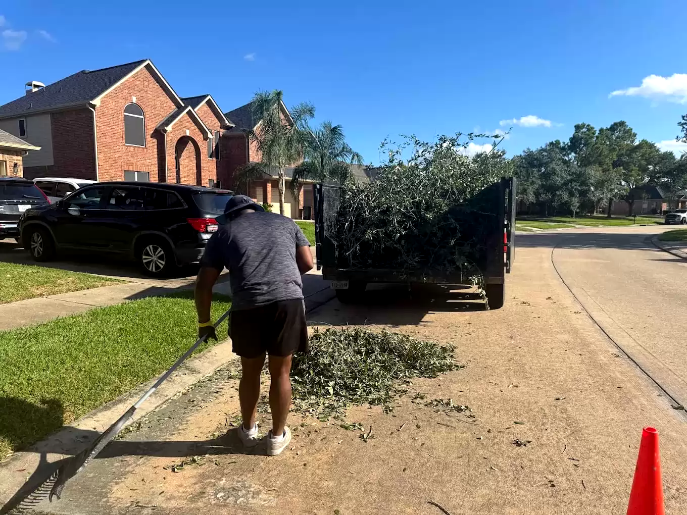 Worker clearing small branches beside a loaded trailer
