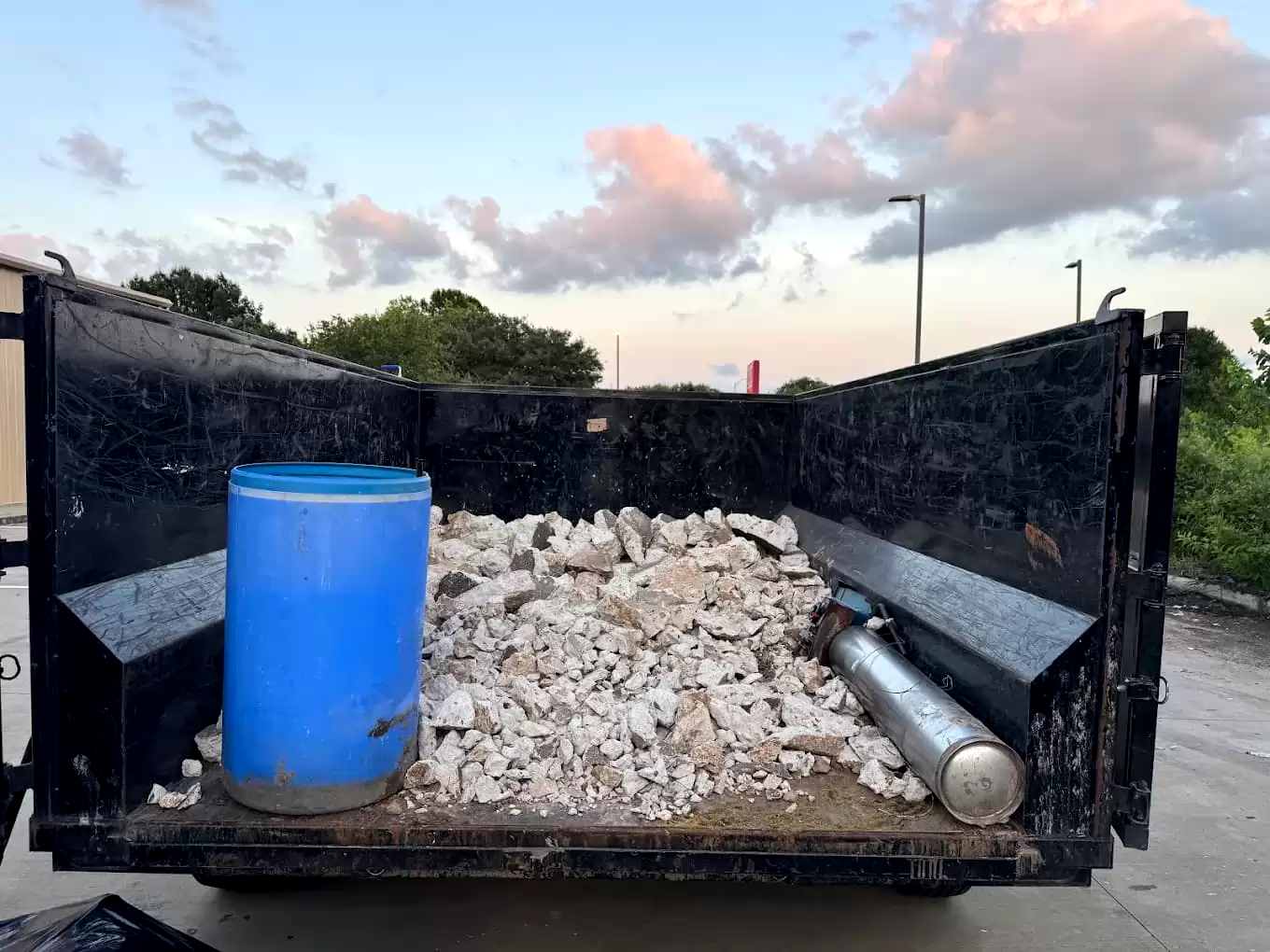 Concrete rubble and a blue barrel inside a dump trailer