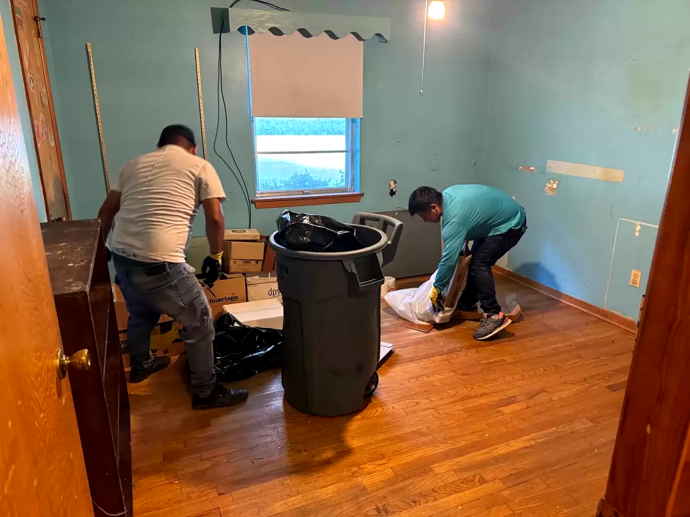 Two workers removing debris from a room