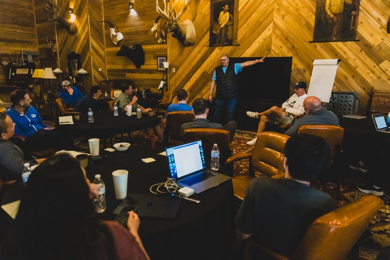 Operators with laptops open in a lodge-style mastermind room