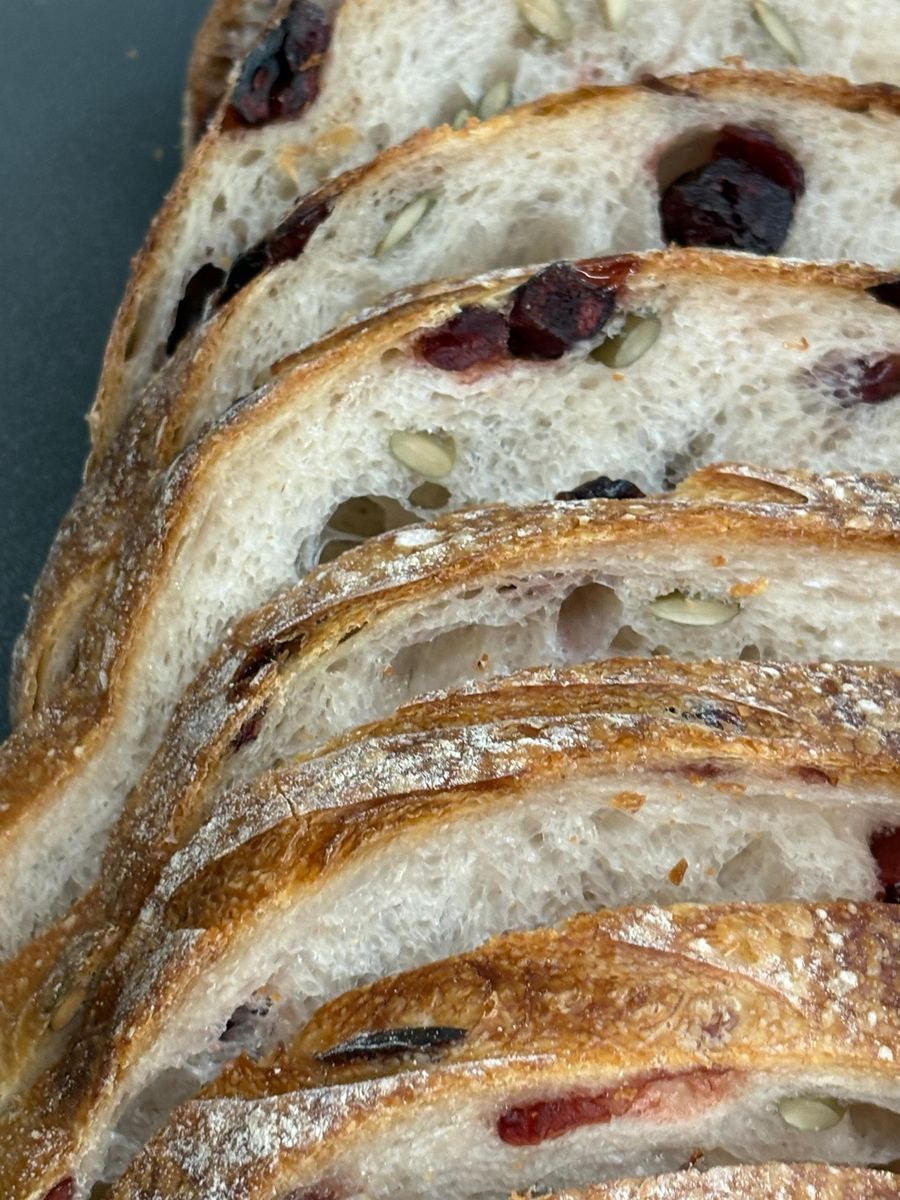 Cranberry sourdough sliced and fanned out, showing the soft open crumb inside a crackly crust