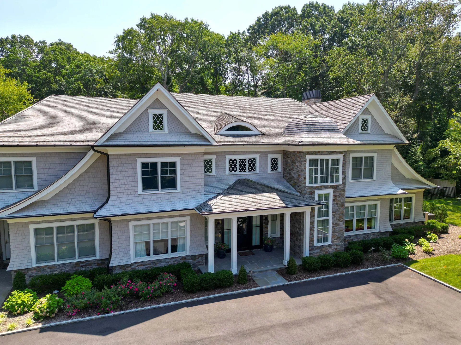 Brookville Cedar Estate, a Prestige custom home in Brookville NY: the cedar-shingle front elevation and gabled entry, photographed from above the drive