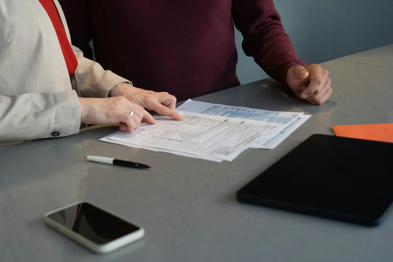 Two people at a meeting table reviewing papers together