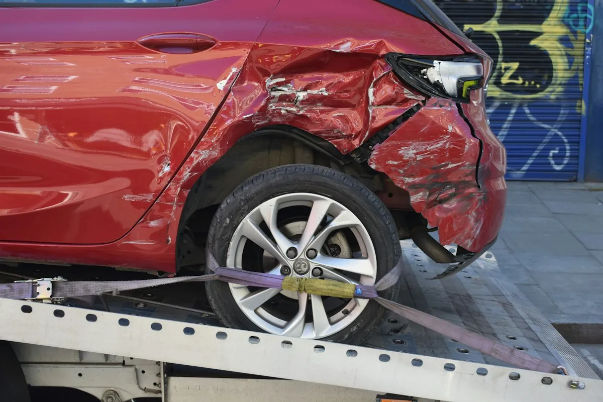 A damaged red car on a tow truck