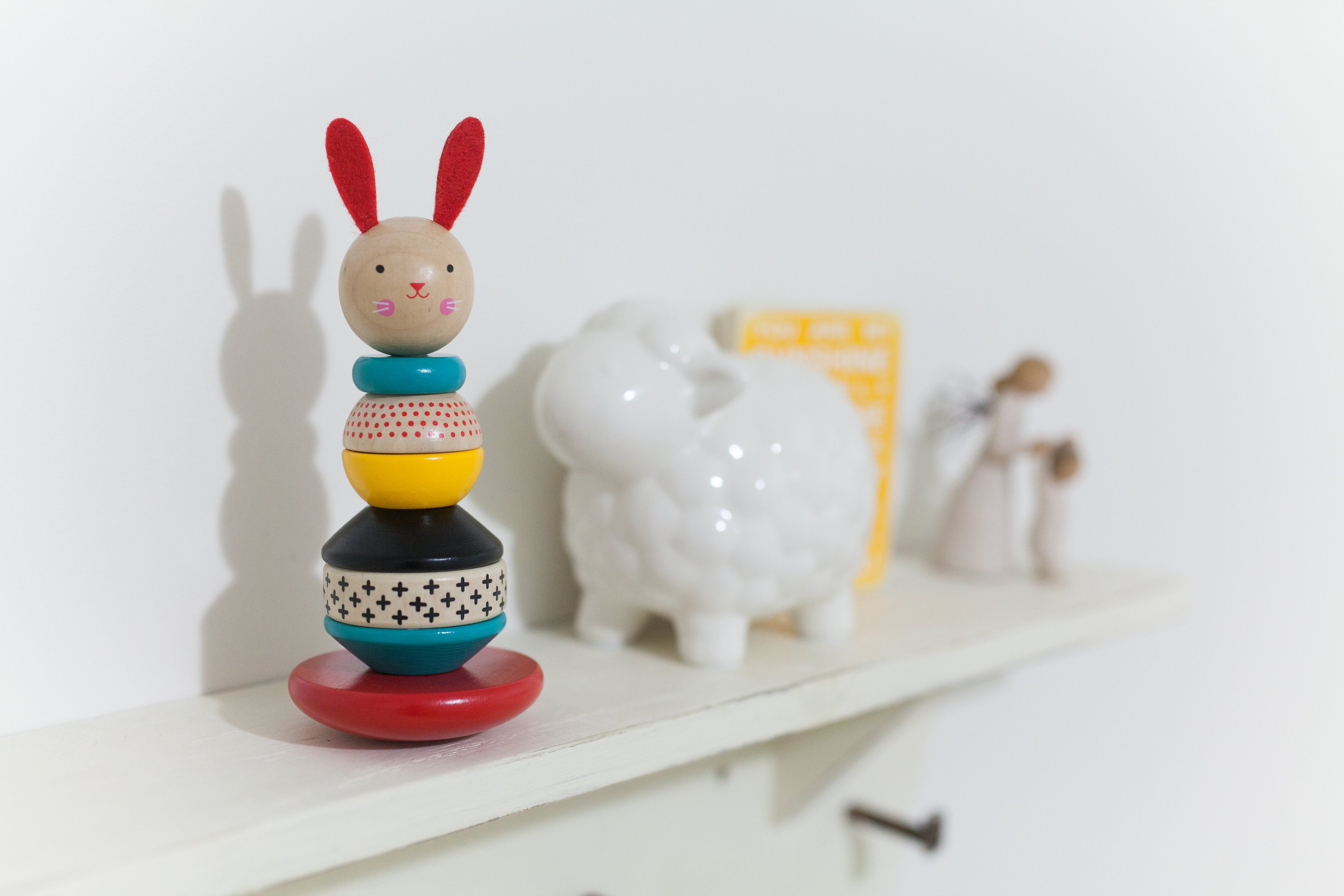 A wooden bunny toy and a ceramic lamb on a nursery shelf