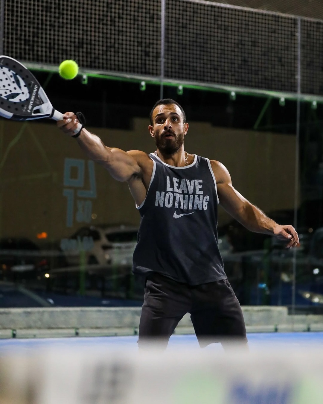 Players diving for a padel shot under lights