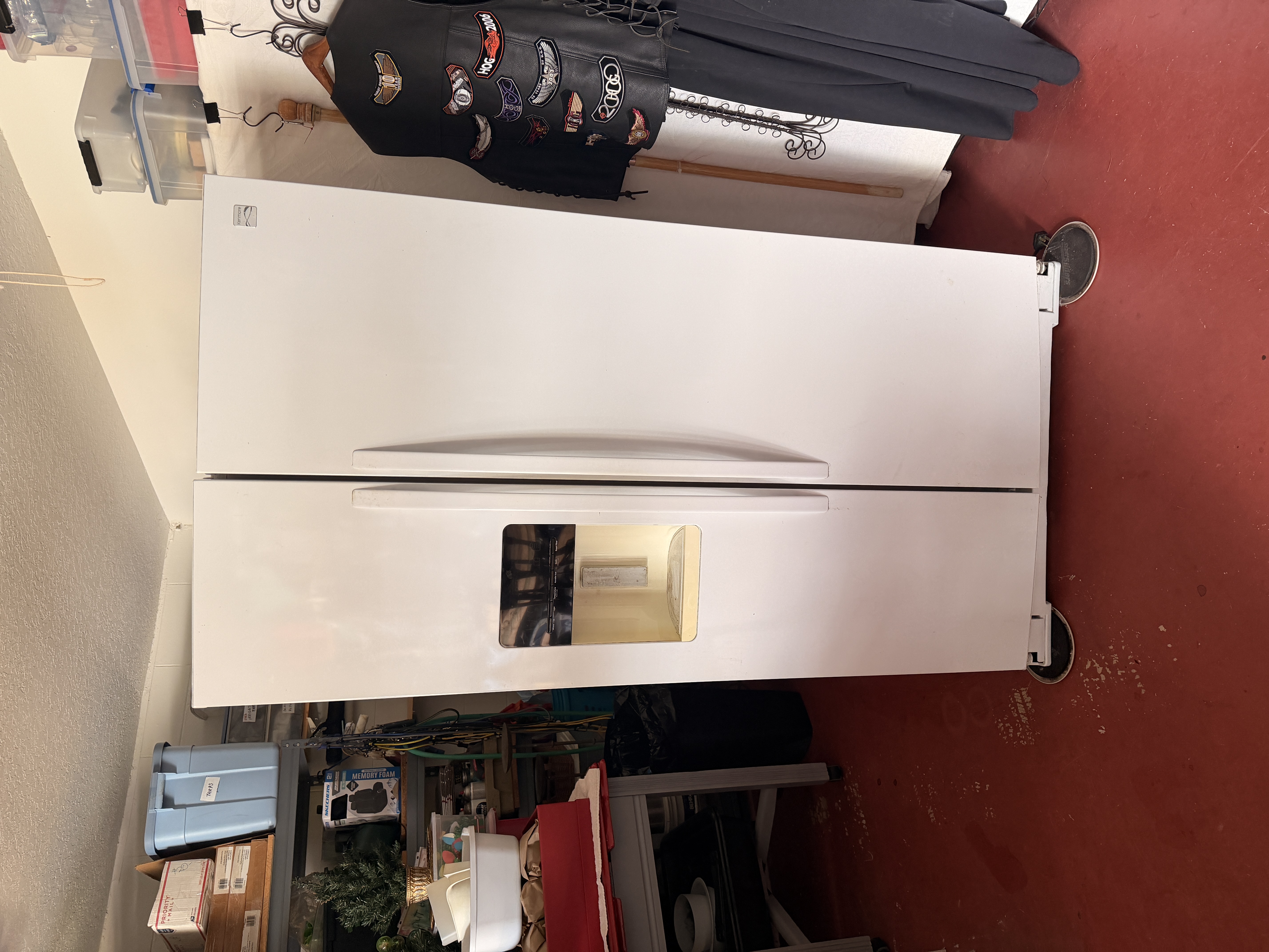 White side-by-side refrigerator standing in a storage area before pickup.