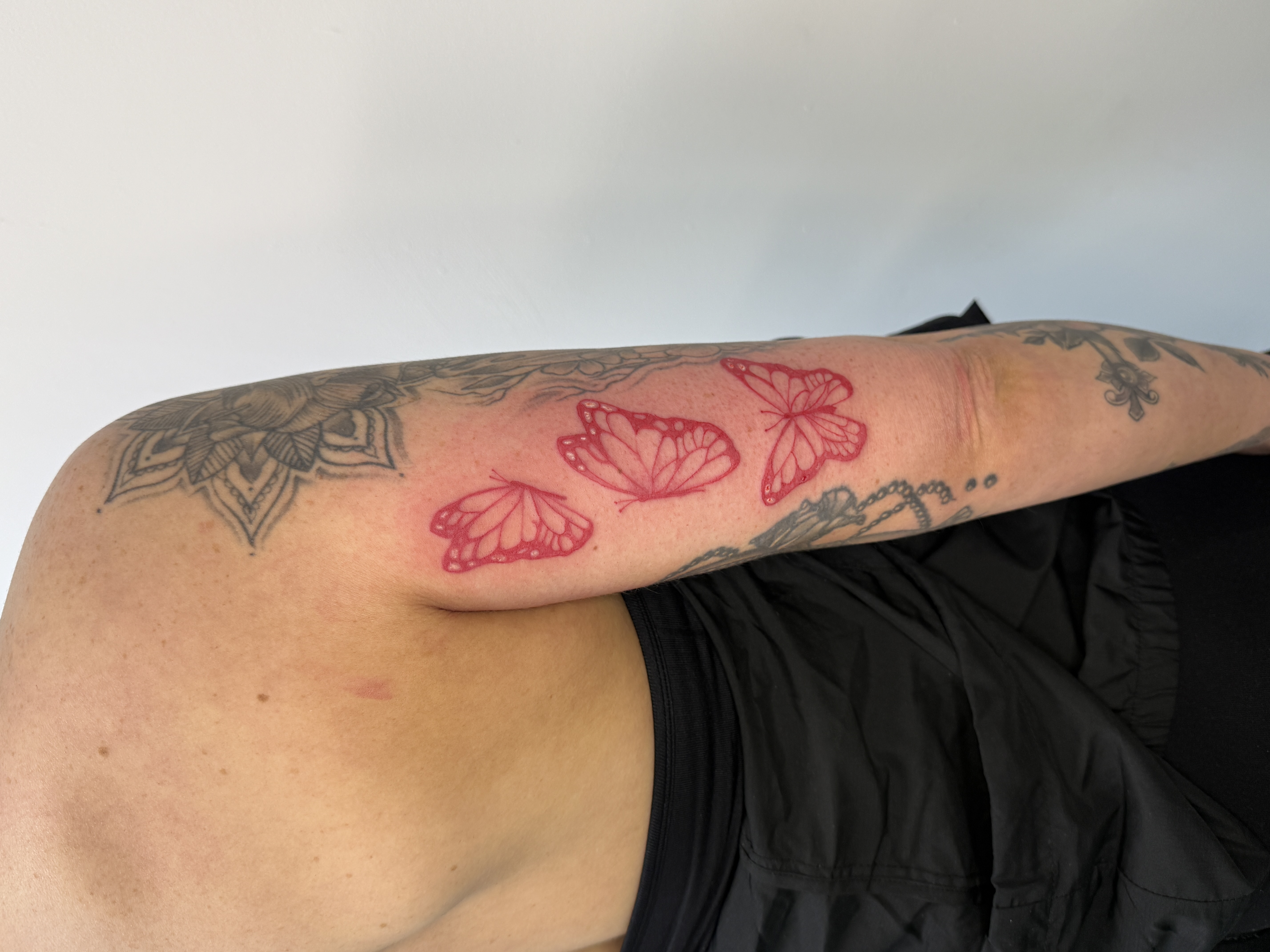 Red ink butterfly and mandala shoulder tattoo by XXII Ink