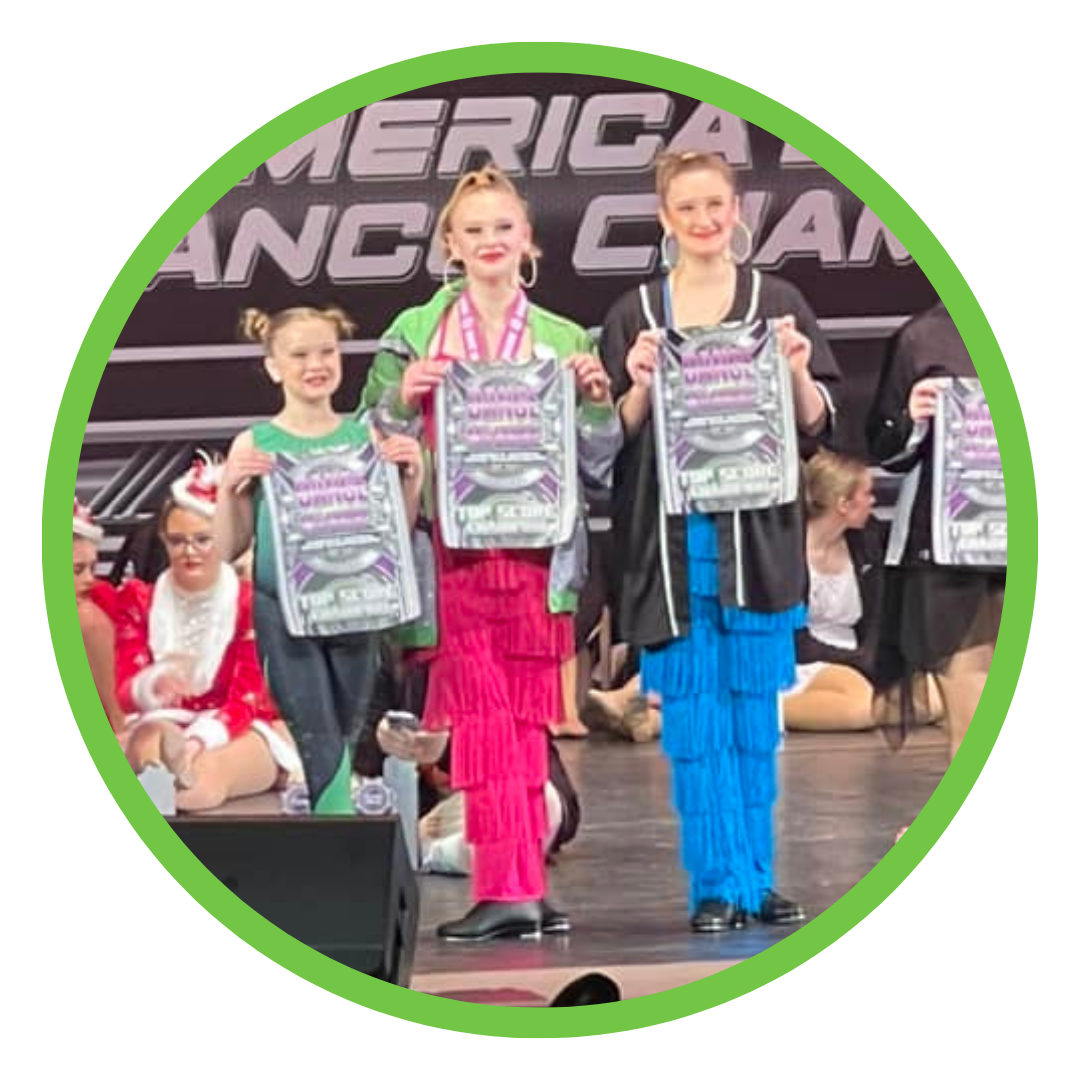 Three dancers who are posing with awards on stage