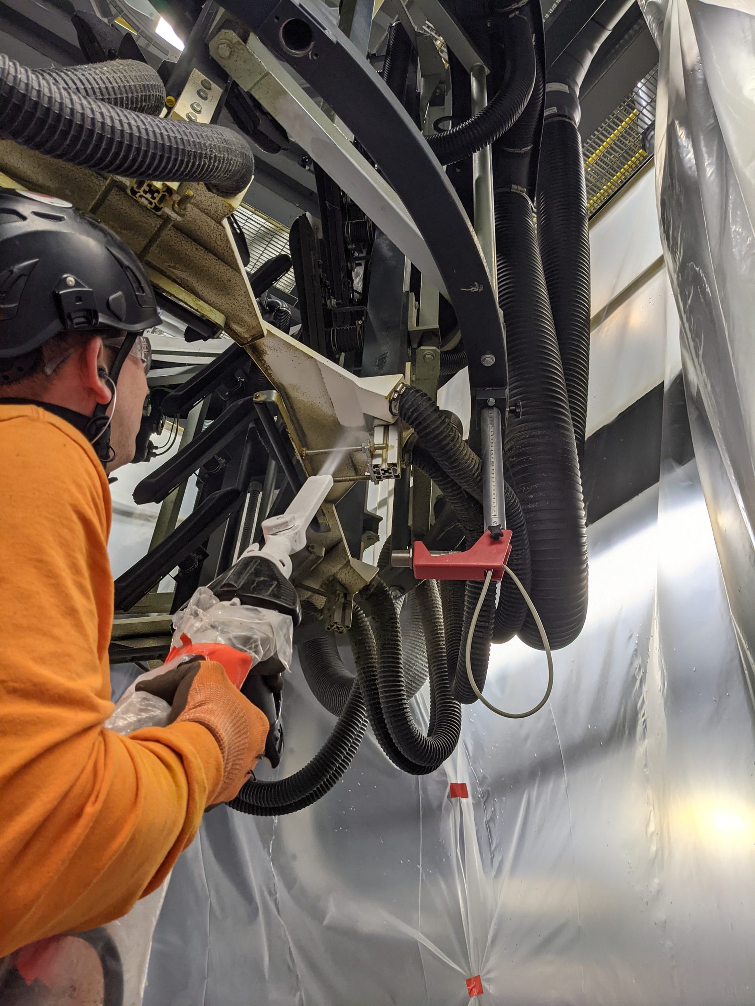 Close up as a CMI tech hits film-line tooling with the dry ice gun, vapor coming off the arm.