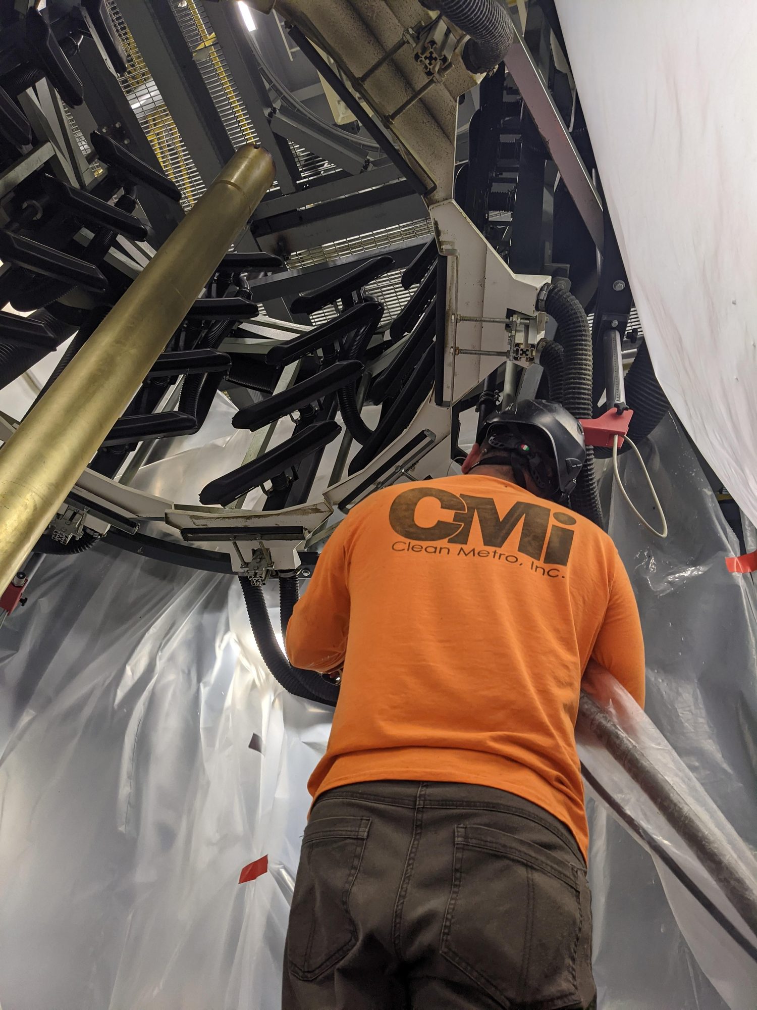 CMI technician dry ice blasting a film tower cooling ring inside plastic containment on an extrusion line