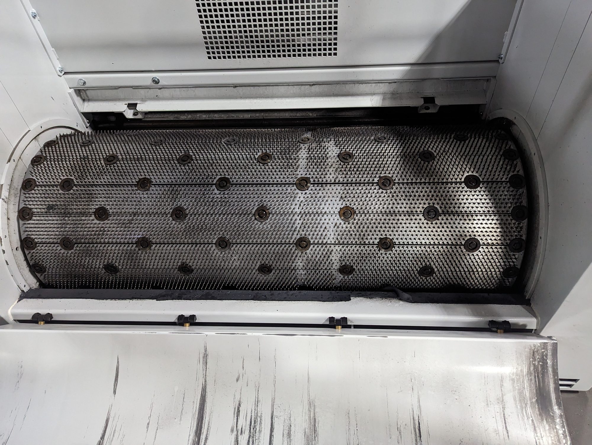 The same perforated drum after dry ice blasting, with the holes open and the metal back to bare steel.