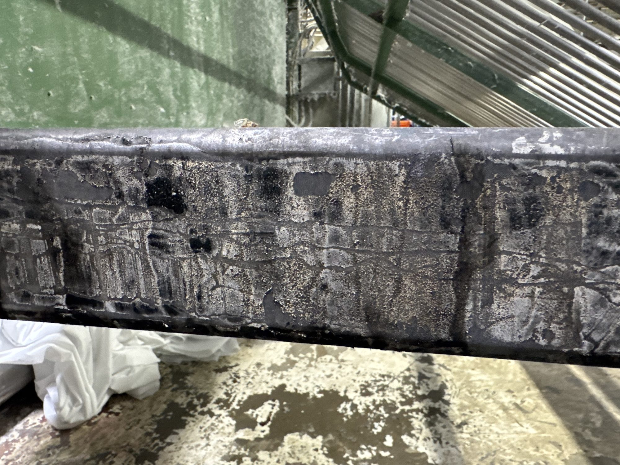 A lint- and residue-crusted steel beam before laser cleaning.