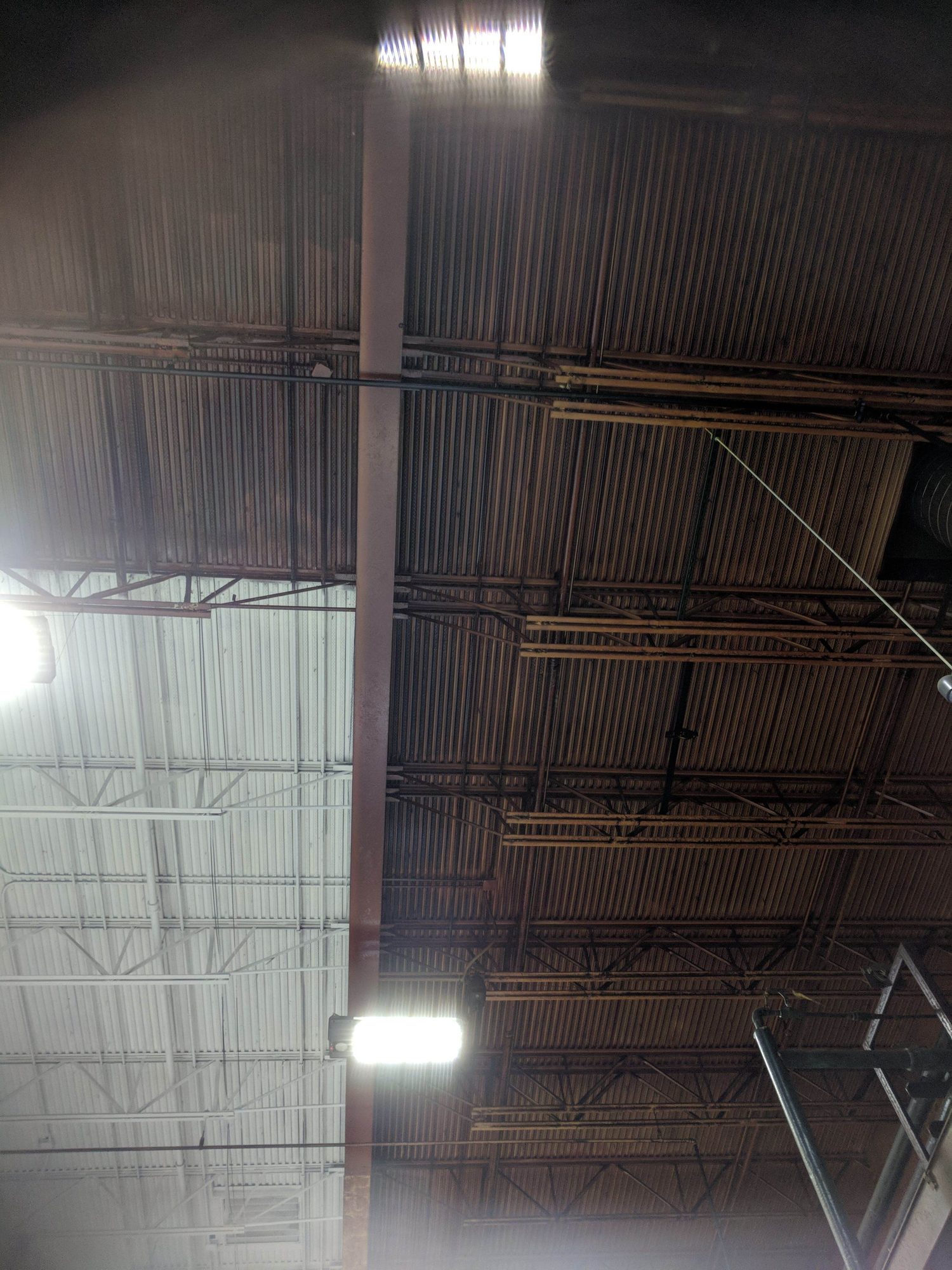 Roof deck line where new white coating meets the original rust-brown steel.