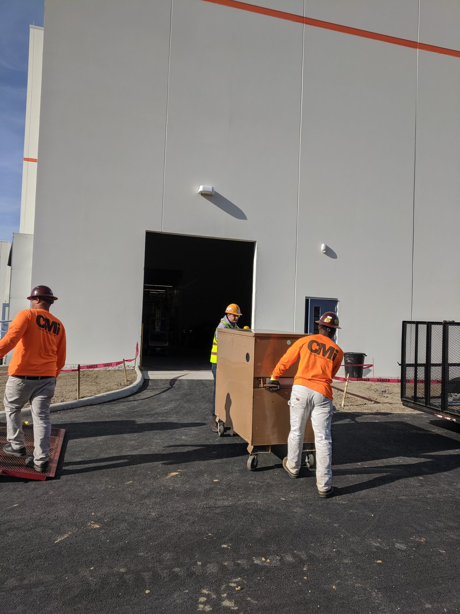 CMI crew in branded shirts roll a job box into a new plant to mobilize for final clean.