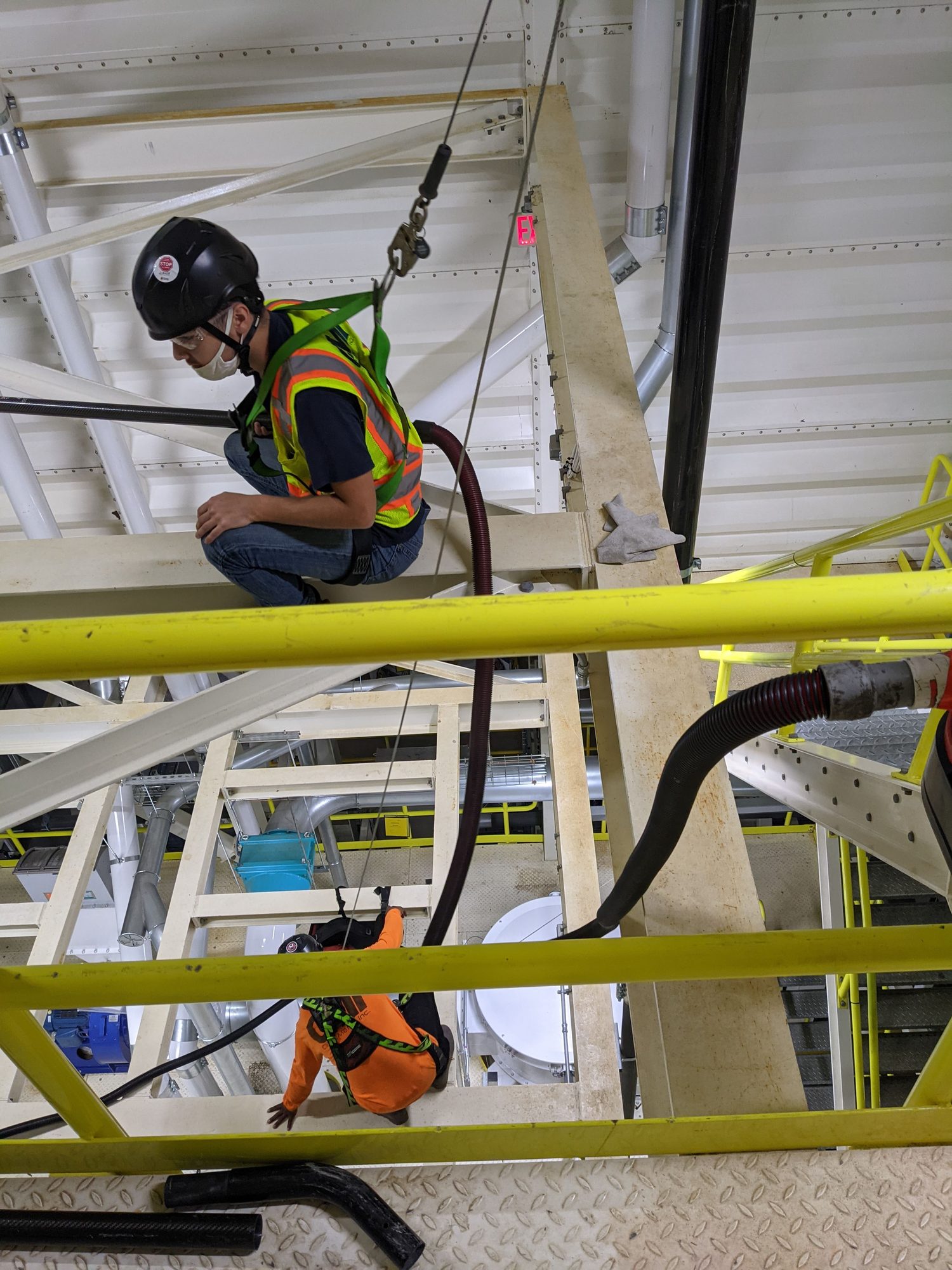 CMI technician tied off on an elevated platform with a vacuum hose
