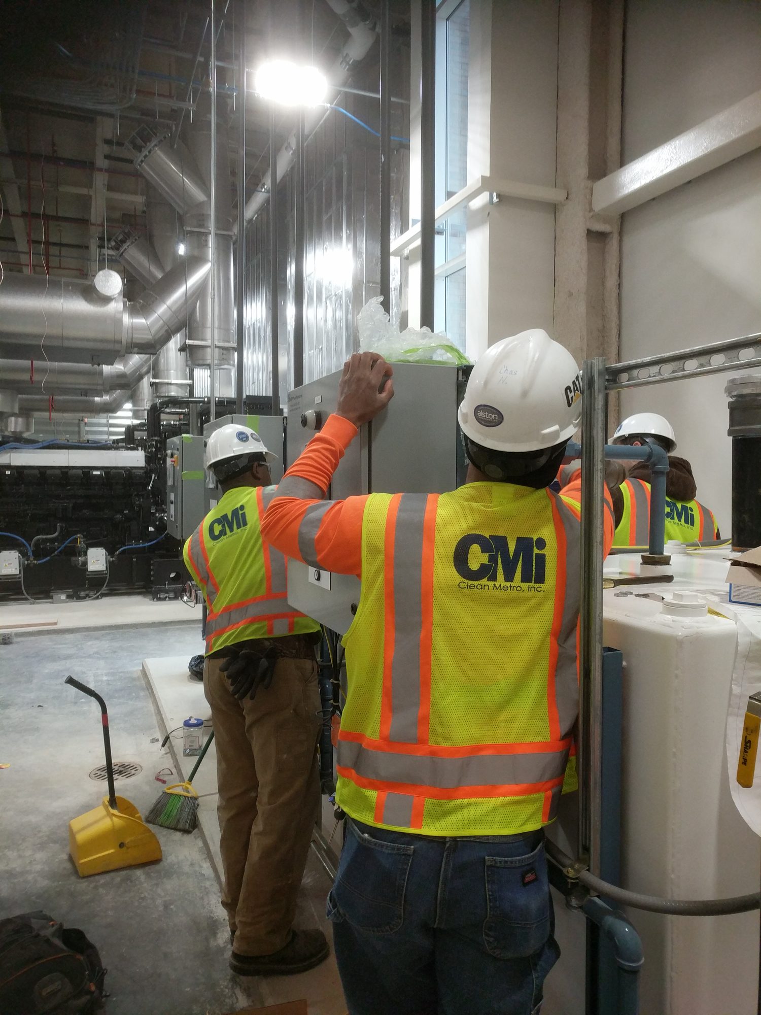 Clean Metro crew in hi-vis vests working on equipment in a central utility plant mechanical room
