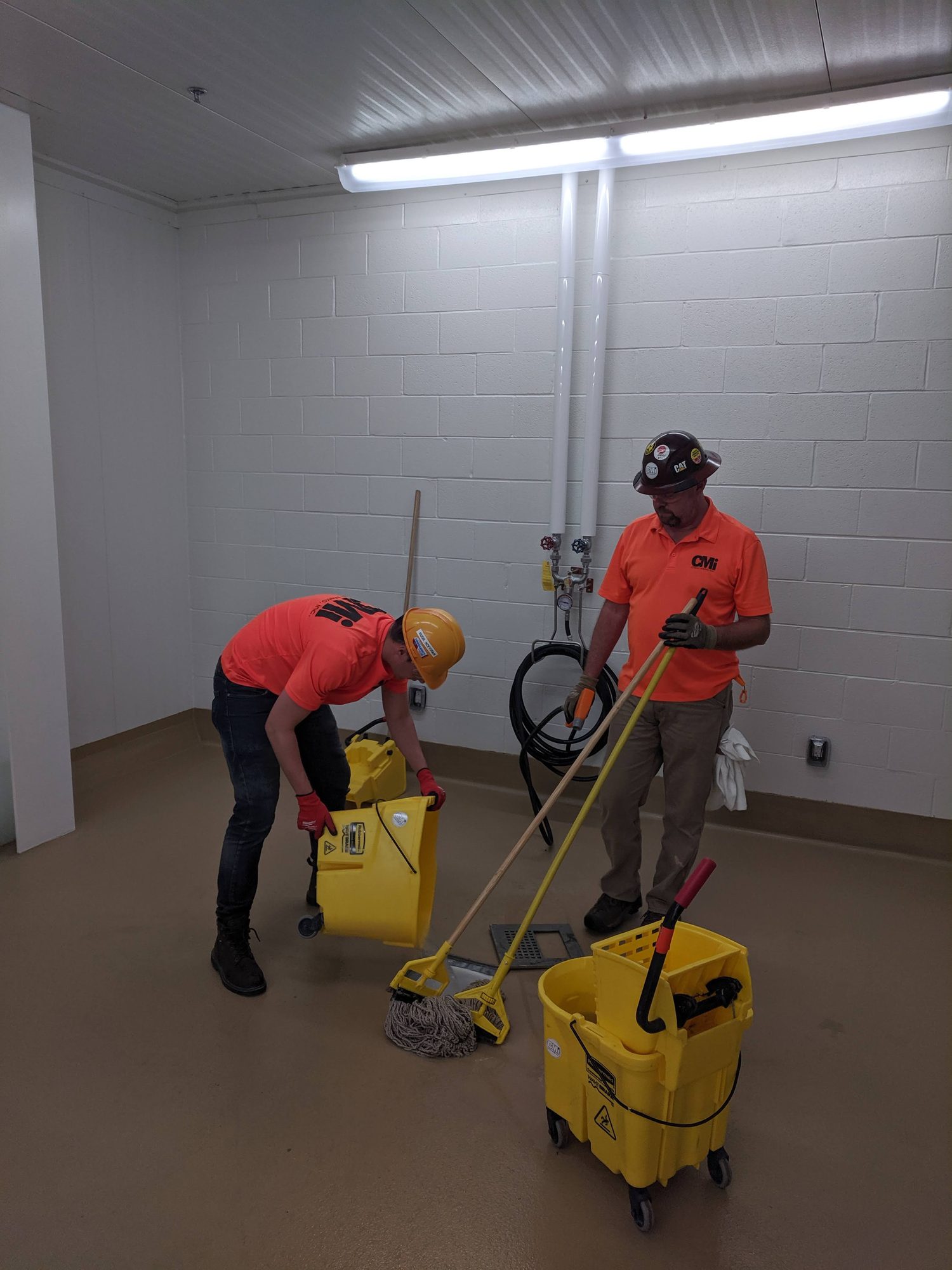 Two CMI techs mop and wring out in a newly finished room.