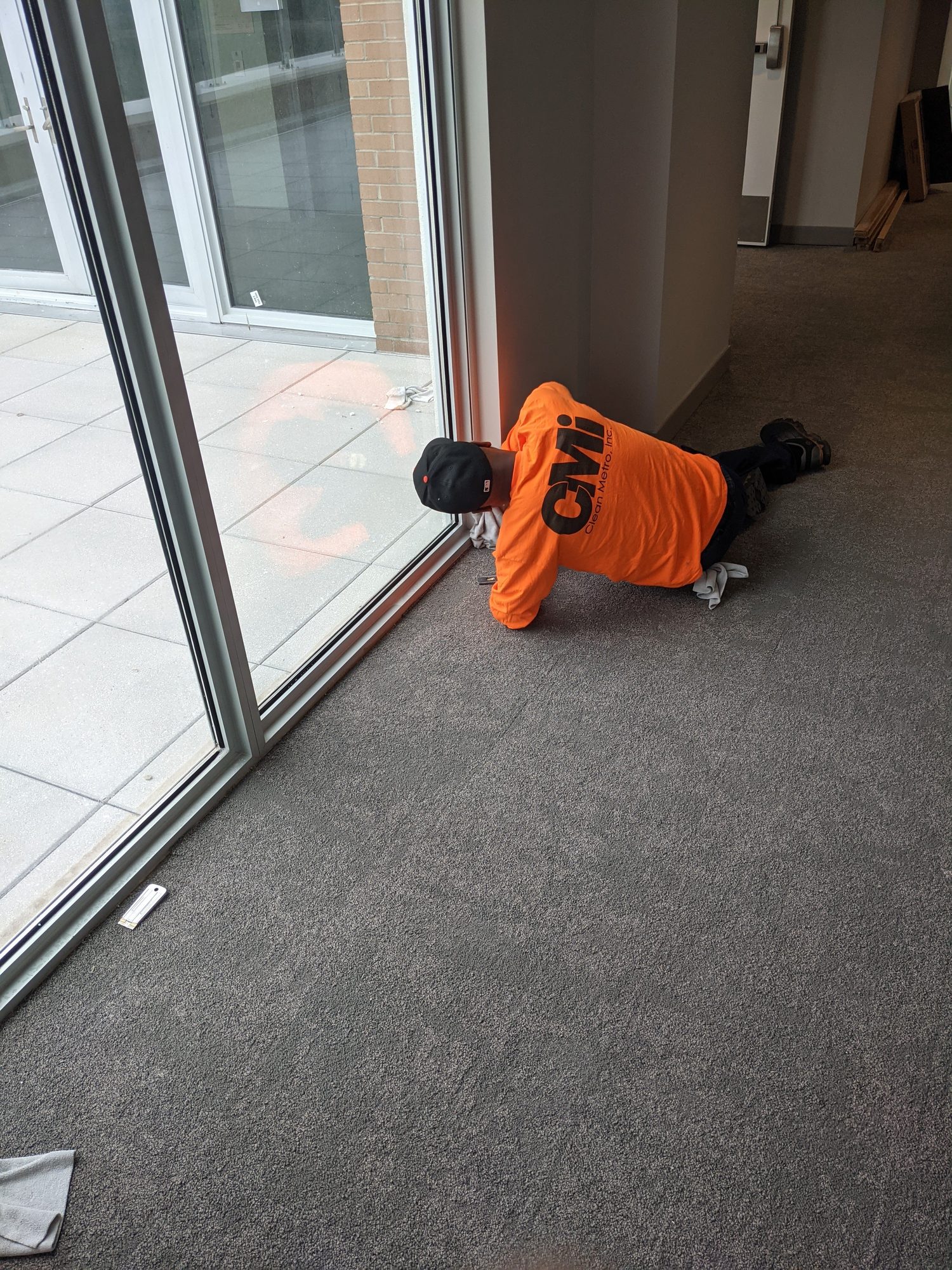A CMI tech details the threshold of a new glass storefront door during final clean.
