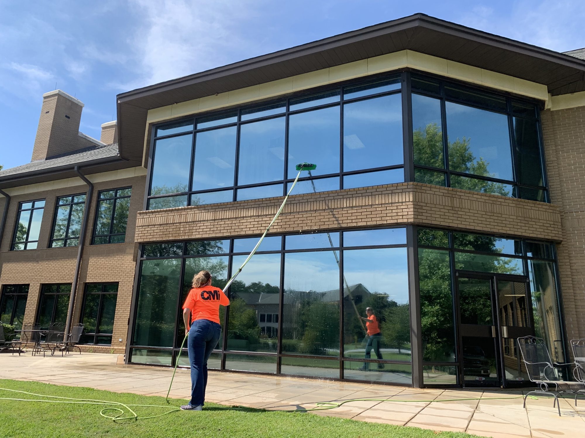 Clean Metro technician cleaning office building glass with a water-fed pole