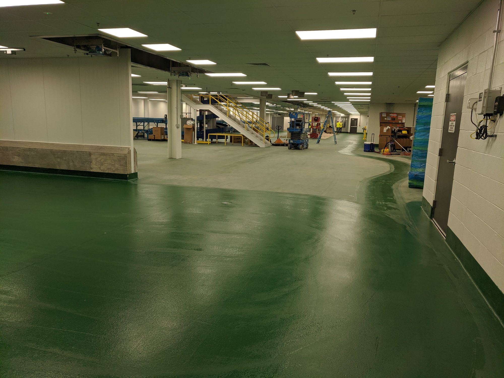 A long run of fresh green epoxy floor, cleaned and ready for turnover in a new food plant.