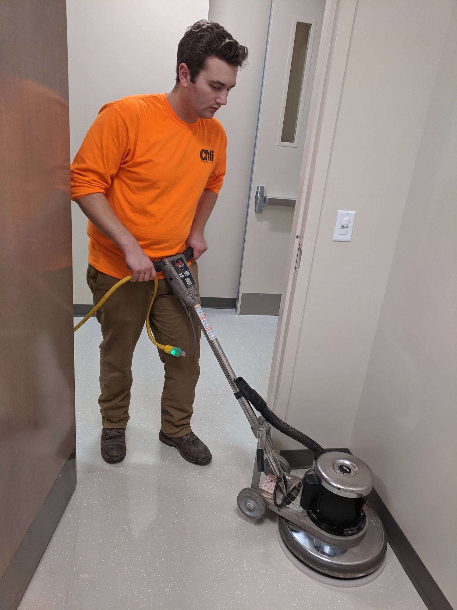 CMI technician running a floor machine during a final clean