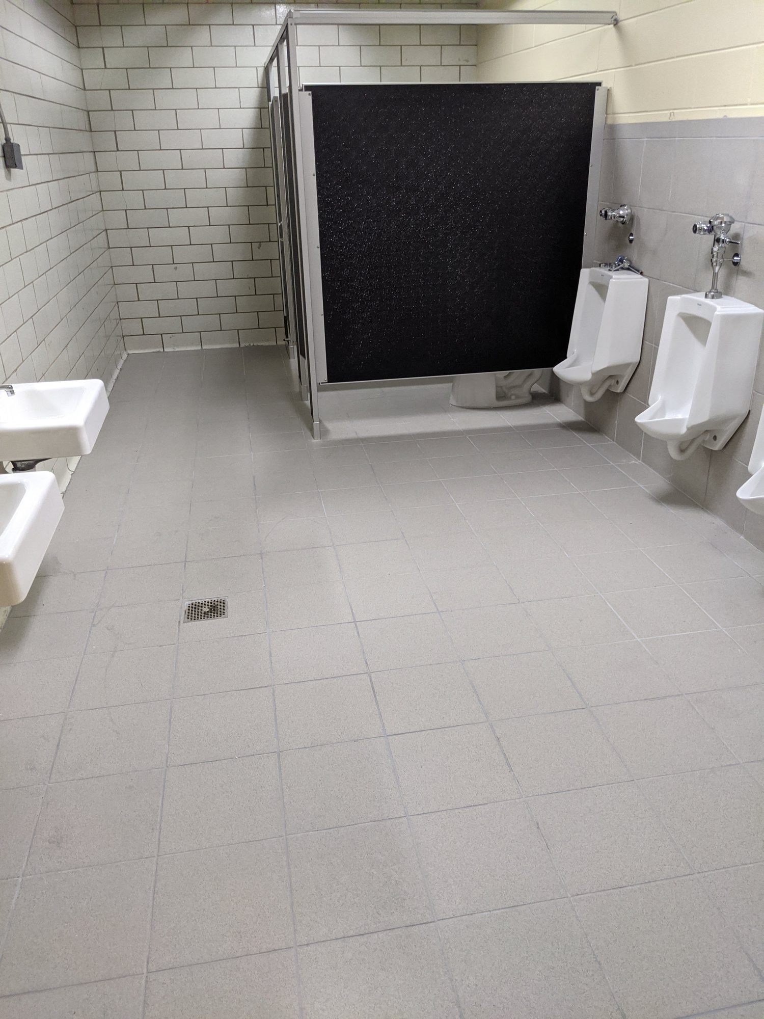 Renovated school restroom with new tile, partitions, and fixtures after CMI's final clean.