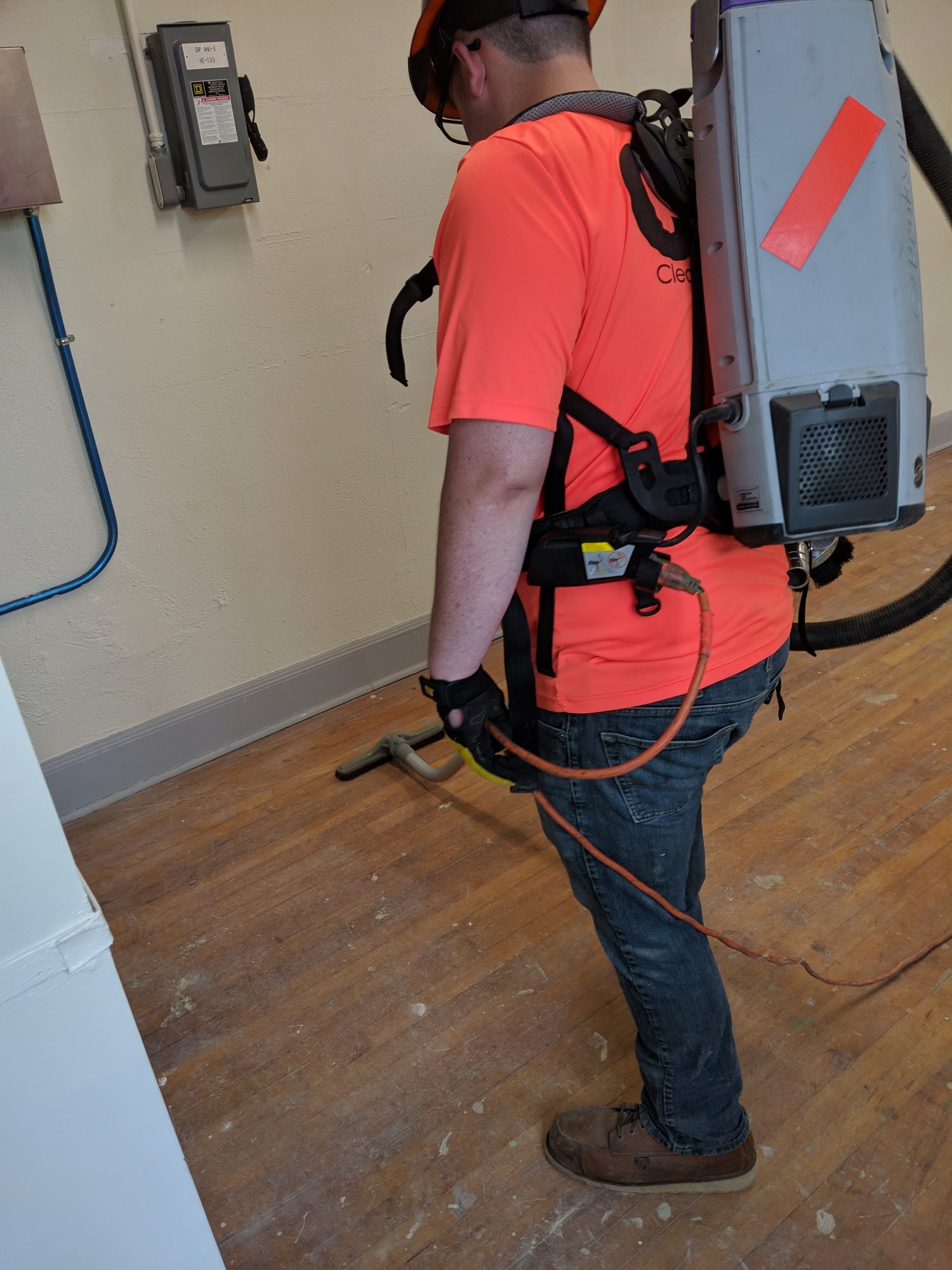CMI tech vacuums a wood-floor room with a backpack HEPA vacuum.