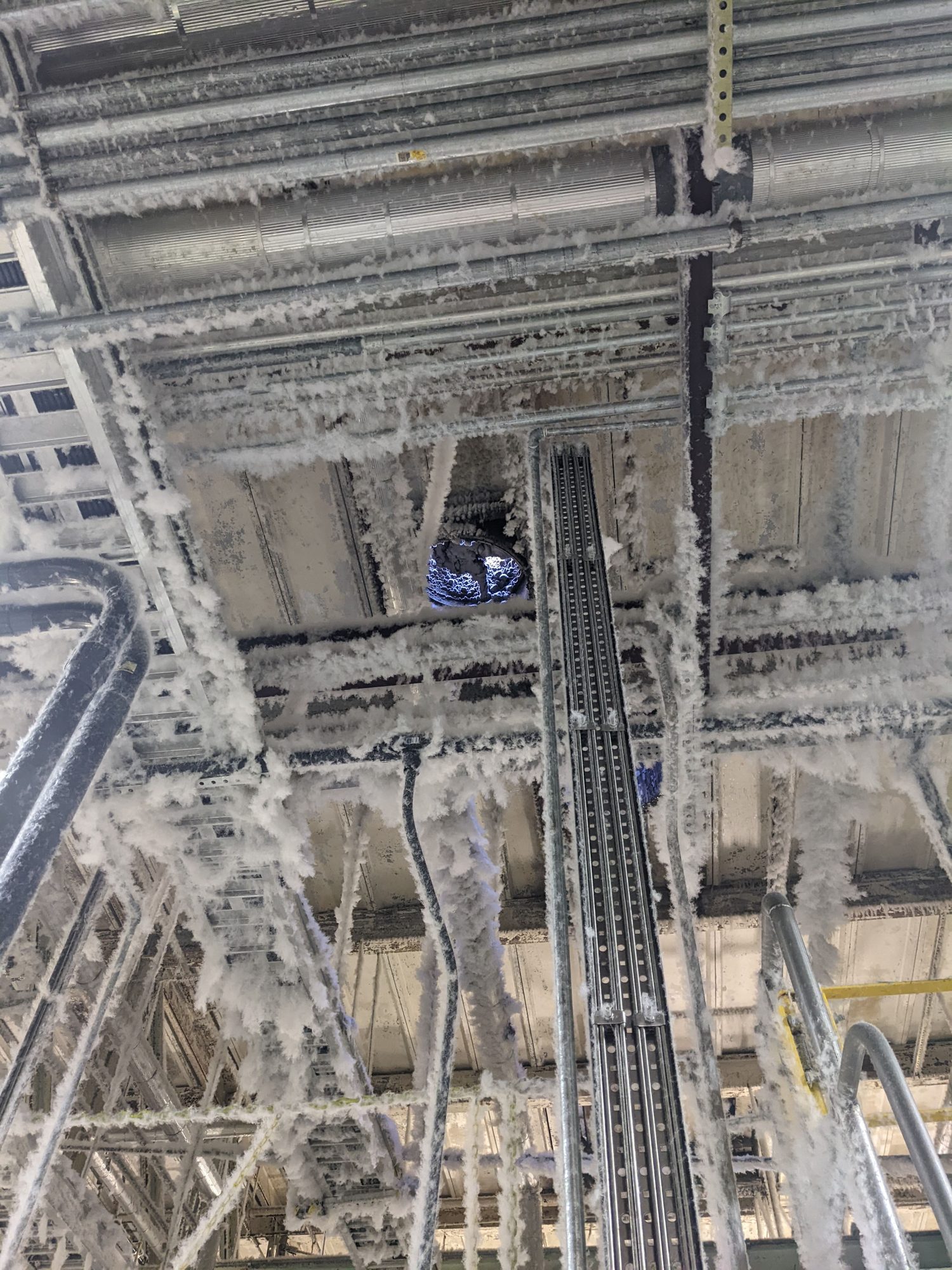 Cotton lint hangs off every overhead pipe, cable tray and beam in a textile plant before combustible-dust cleaning.